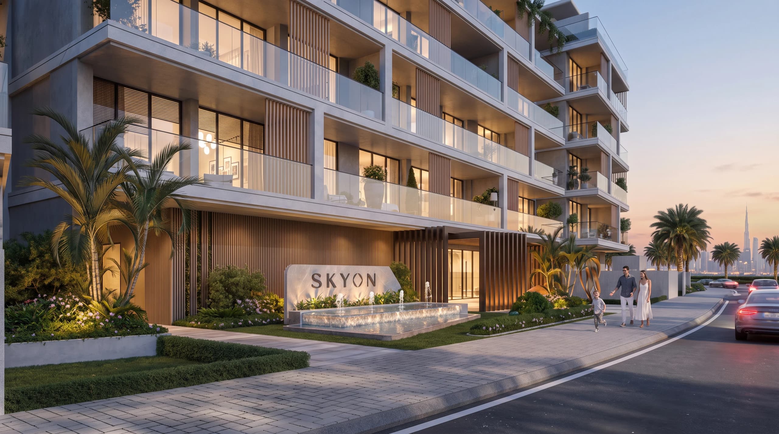 Building entrance with the SKYON sign, a water feature and a landscaped path at dusk
